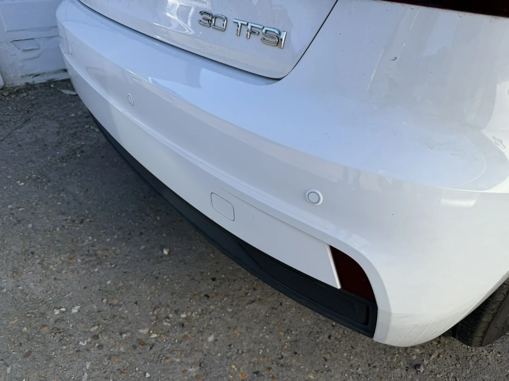 Colour matched rear parking sensors fitted into the white bumper of an Audi