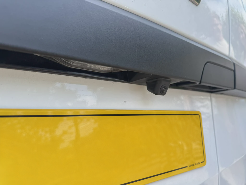 Close-up of a compact reversing camera fitted above a rear number plate